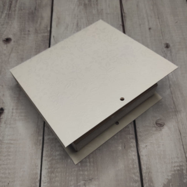 Scatola media a forma di libro in cartoncino a fantasia floreale tono su tono bianco. Disponibile anche piccola e grande