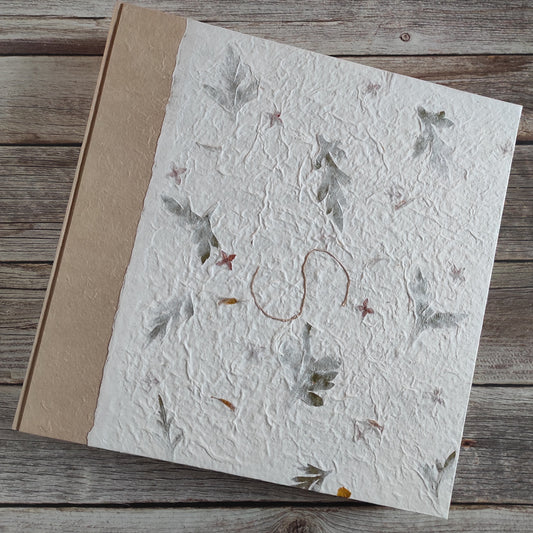 Copertina album fotografico artigianale in carta di gelso botanica con petali gialli e foglie verdi su fondo avorio